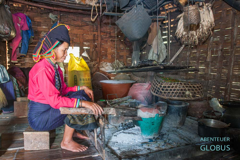 Frau der Ethnie Tai Dam sitzt an der Feuerstelle in ihrem Haus in Ban Anoulak.