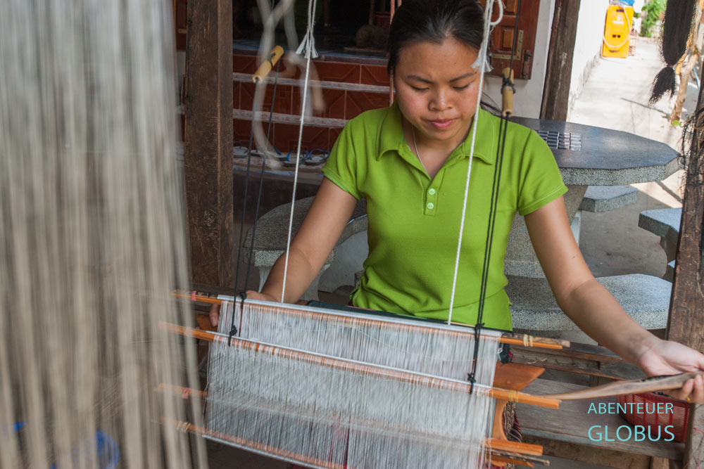 Eine Frau sitzt an einem Webstuhl und webt Seide im Dorf Ban Sop Jam.