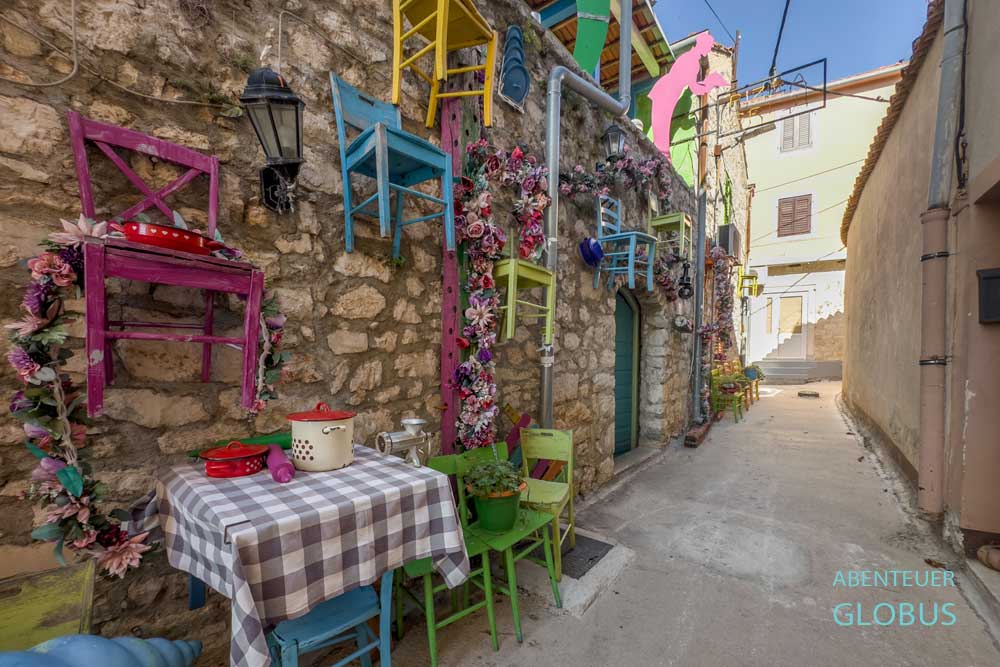 Bunte Stühle an der Wand des Restaurants Europa in einer Gasse der Altstadt von Biograd na Moru in Kroatien.