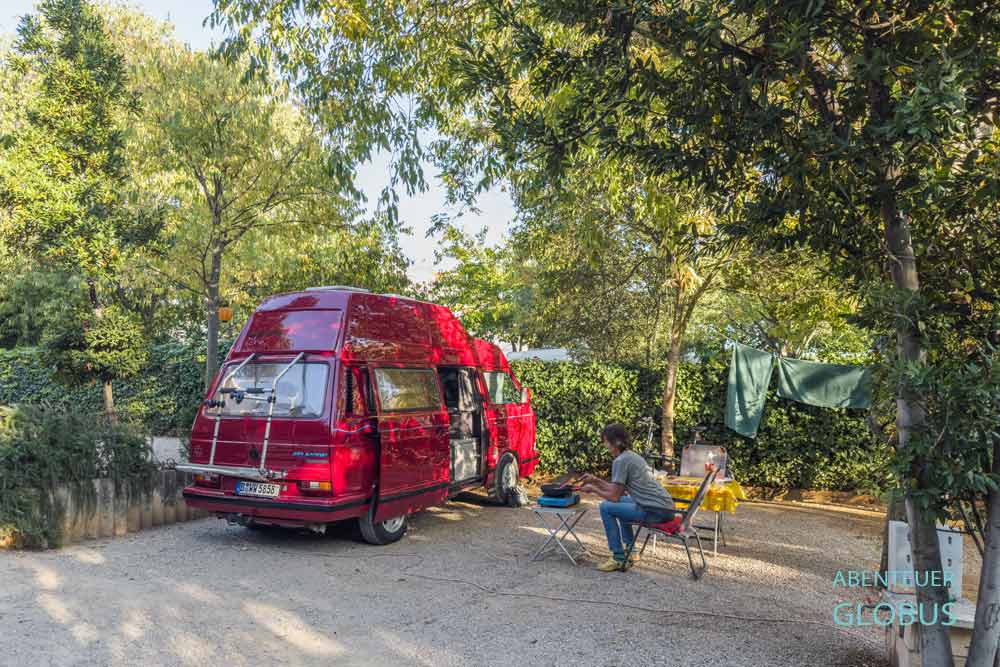 Roter Van auf einem von Bäumen umgebenen Stellplatz auf dem Campingplatz Filip in Sveti Filip i Jakov, Kroatien.