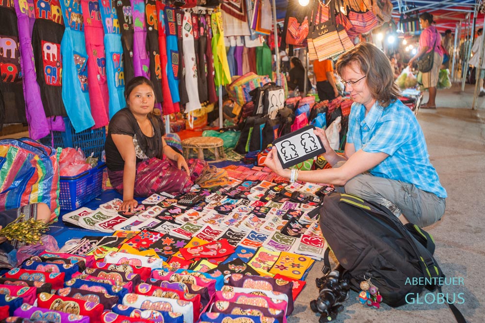 Touristin an einem beleuchteten Verkaufsstand auf dem Nachtmarkt der Sisavangvong Road in Luang Prabang.