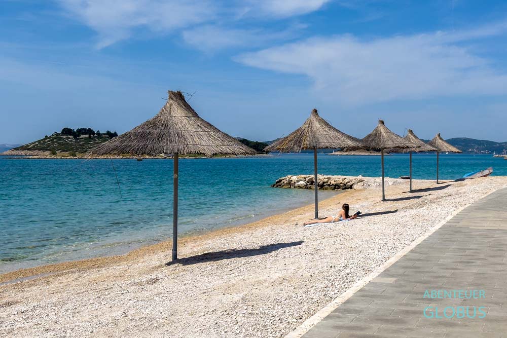 Sonnen am Hauptstrand von Pakostane mit Sonnenschirmen, der Plaza Janice heißt.