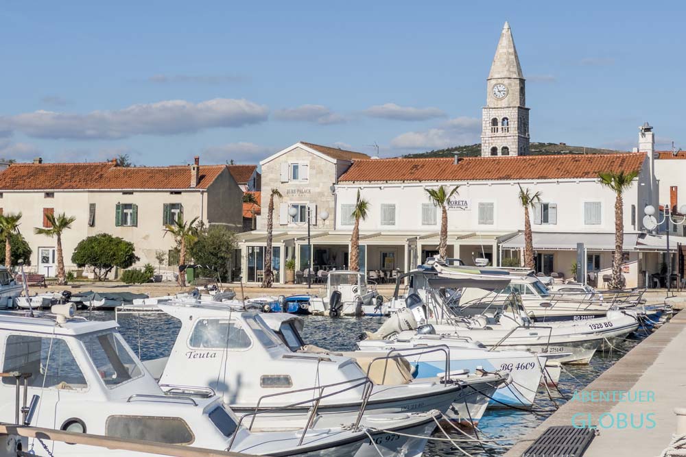 Altstadt von Turanj mit Häusern und Glockenturm der Karmeliterkirche. Im Vordergrund ist der Hafen. 