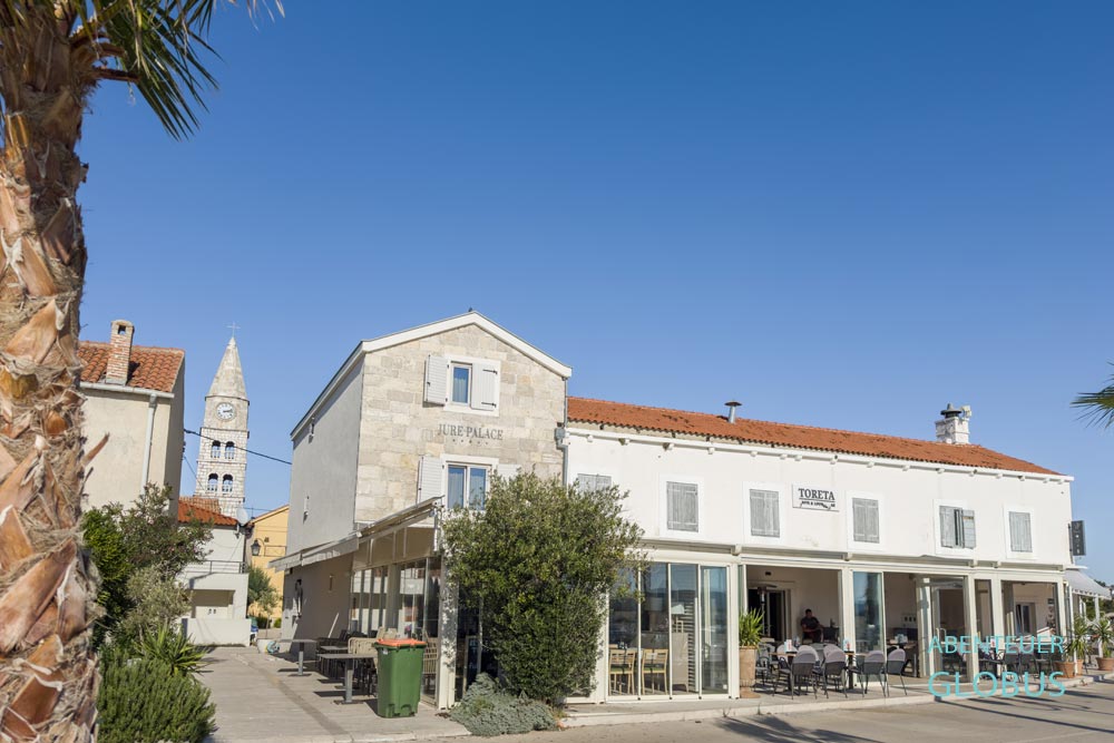 Restaurant an der Uferstraße und Turm der Karmeliterkirche in Turanj