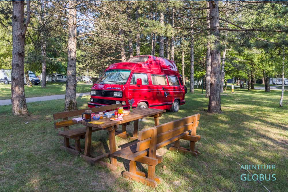 Rotes Wohnmobil auf einem von Kiefern umgebenen Stellplatz auf dem Campingplatz Borje nahe den Plitvicer Seen