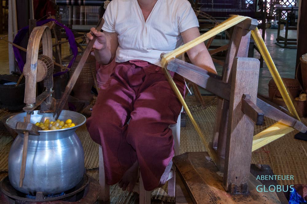 Frau haspelt Seidenfäden von eingeweichten Kokons.