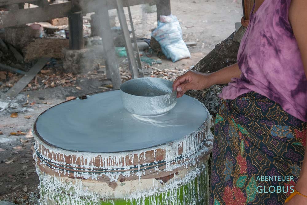 Frau fertigt Reispapier aus Reispaste auf einer beheizten Tonne in Ban Pho bei Muang Thoun.