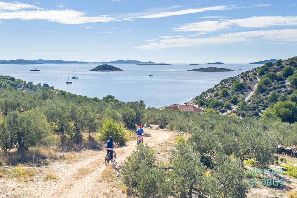 Zwei Fahrradfahrer auf dem Weg zur Bucht Sveti Nikola in Jezera, im Hintergrund die Inseln der Kornaten