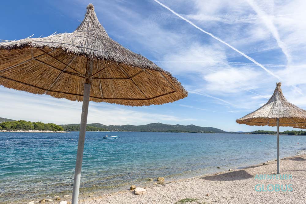 Strand Plaza Kucina mit Sonnenschirmen in Jezera auf der Insel Murter