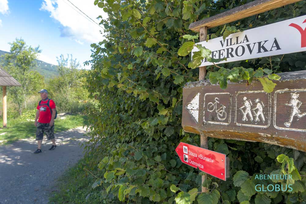 Person auf einem Weg mit Hinweisschildern für Wanderer und Radfahrer in Kulen Vakuf