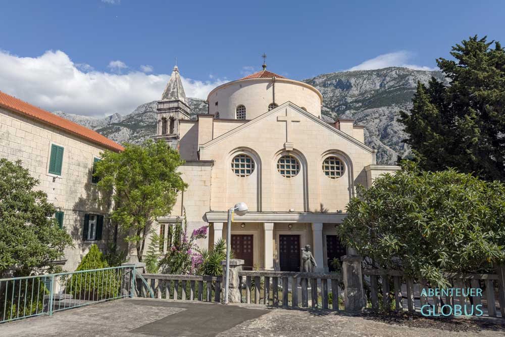 Kirche der Heiligen Jungfrau Maria des Franziskanerklosters in Makarska mit Glockenturm und Biokovo-Gebirge im Hintergrund