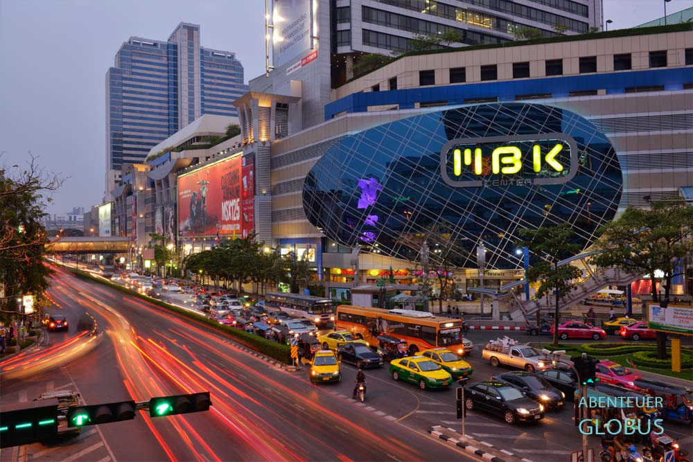 Beleuchtetes MBK Center in Bangkok am Abend mit Verkehr im Vordergrund