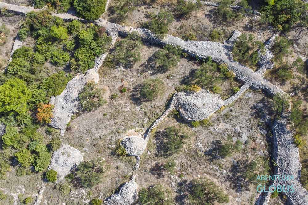 Steinmauern und Steinhügel zwischen Olivenbäumen auf der Insel Murter, Kroatien