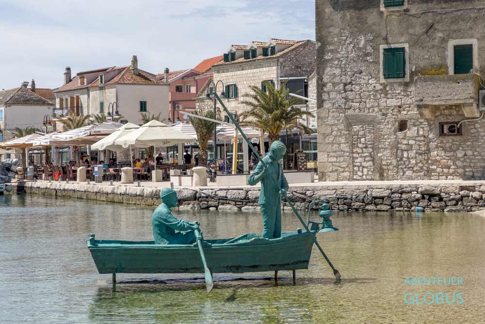 Denkmal „Ribar pod Osti“ mit zwei Fischern im Boot im Hafen von Primosten, Kroatien