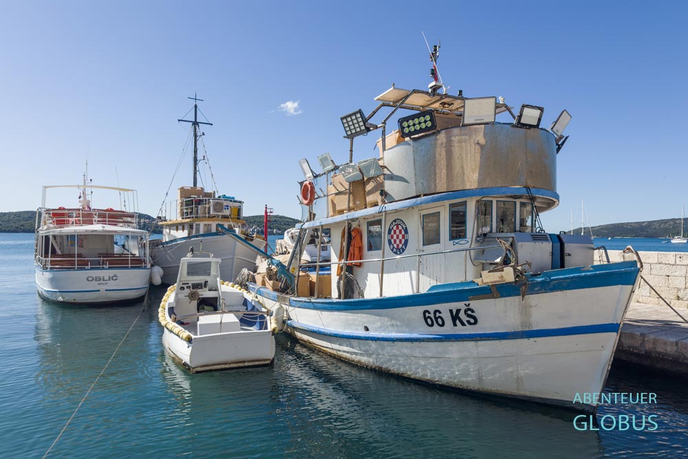 Boote und ein Fangschiff im Hafen von Seget Donji, Kroatien
