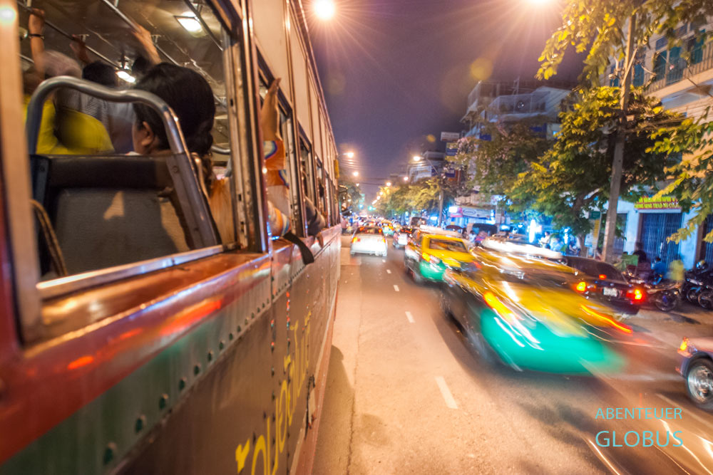 Taxis und Busse im öffentlichen Nahverkehr am Abend auf einer Straße in Bangkok, Thailand