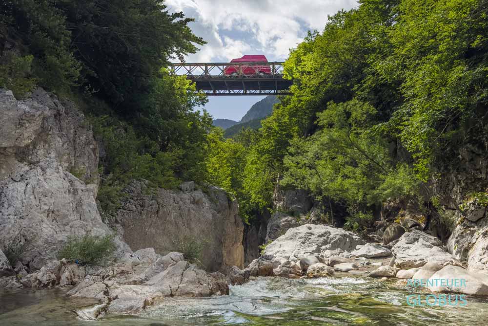 Roter Camper auf einer Brücke über dem Bashkimit Canyon bei Vermosh