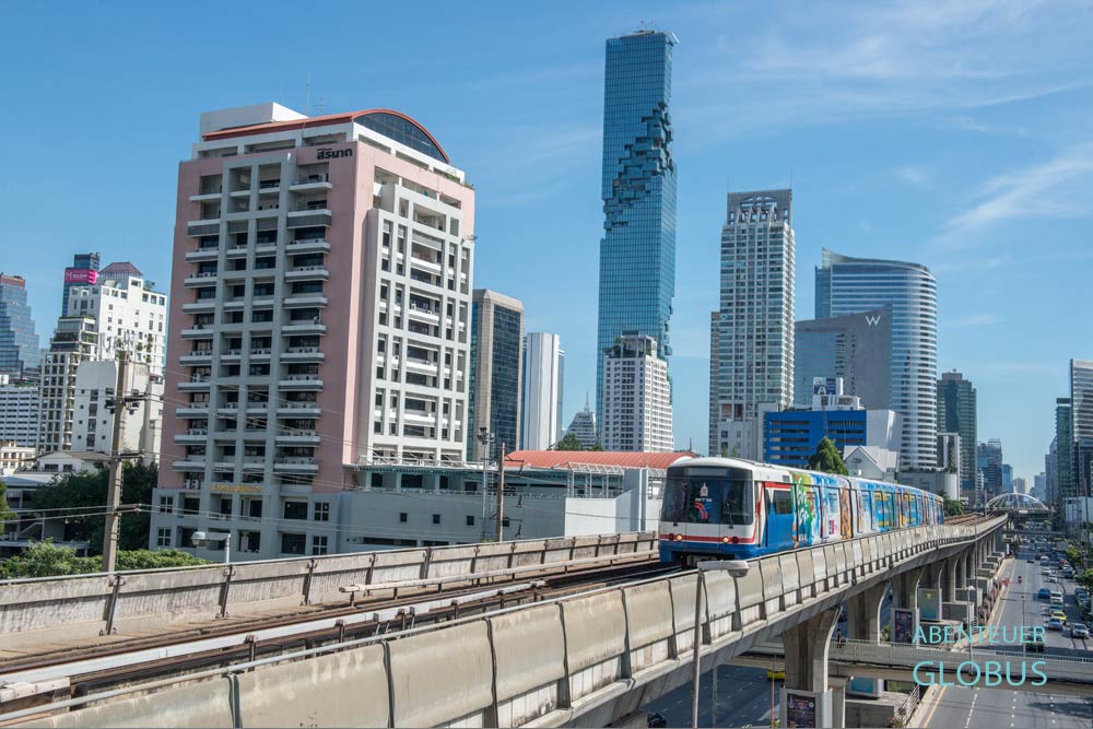 BTS Skytrain auf den Schienen, im Hintergrund das Hochhaus King Power Mahanakhon in Bangkok, Thailand