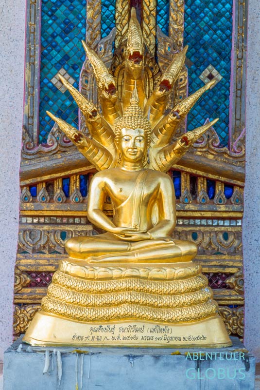Goldene Buddha-Statue mit Naga-Schlangen im Tiger Cave Tempel (Wat Tham Suea) in Kanchanaburi, Thailand.