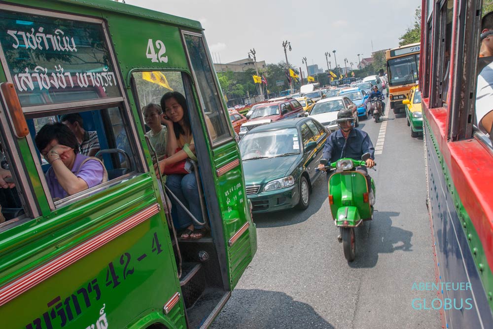 Stau im Straßenverkehr in Bangkok mit zwei Stadtbussen im Vordergrund und einem Motorroller in der Mitte, Thailand