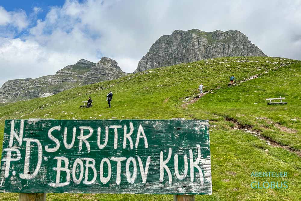 Grünes Holzschild am Wanderweg zum Gipfel Bobotov Kuk im Nationalpark Durmitor