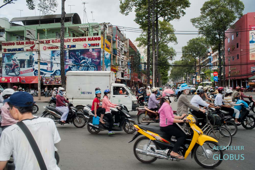Roller und Autos auf einer Straße in Ho-Chi-Minh-Stadt