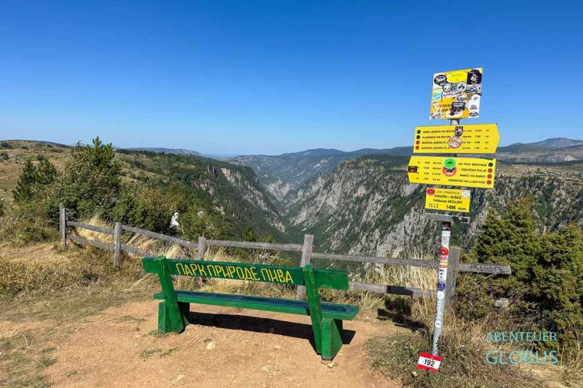Grüne Bank und Wanderschilder am Aussichtspunkt Nedajno, dahinter der Susica Canyon zwischen Naturpark Piva und Durmitor-Nationalpark