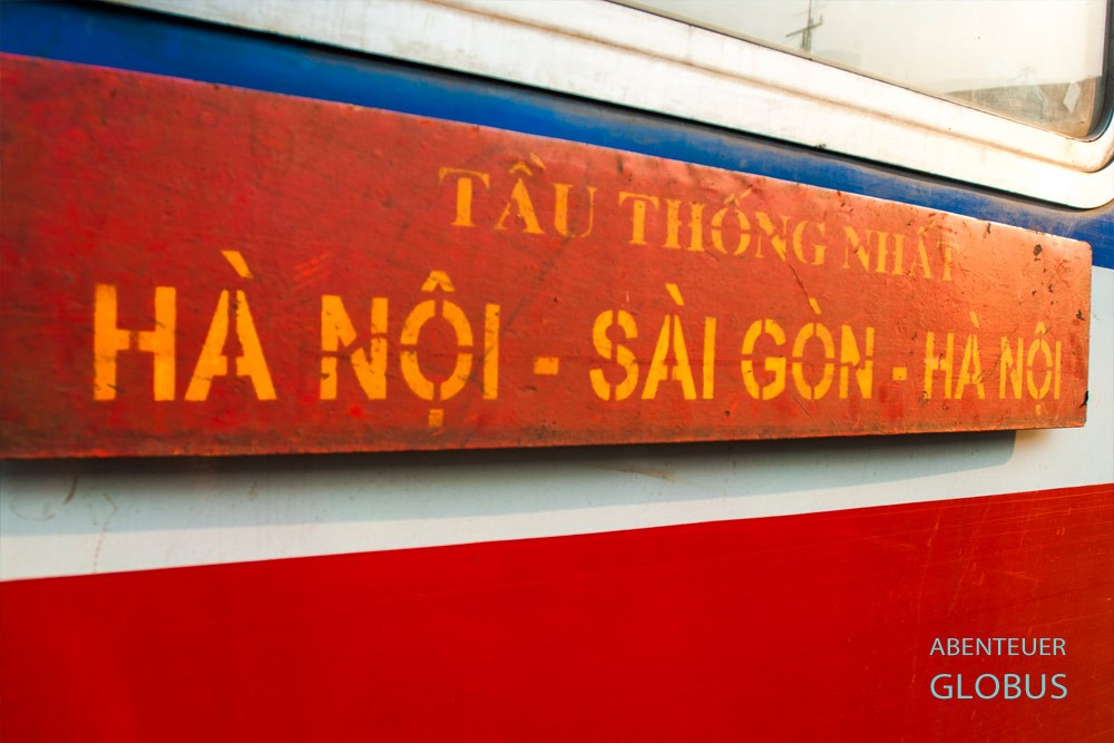 Rotes Schild mit gelber Aufschrift „Hanoi – Saigon – Hanoi“ am Wiedervereinigungsexpress in Vietnam