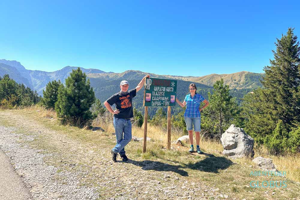 Zwei Touristen an einem Schild vom Nationalpark Durmitor, Montenegro