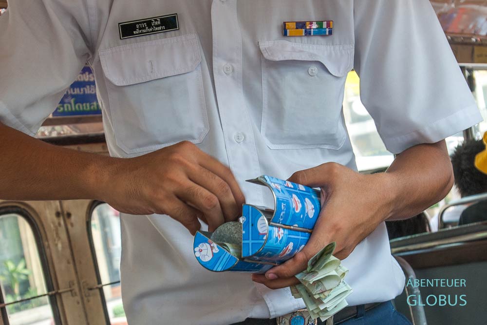 Buskassierer mit Geldbox und Geldscheinen in der Hand in einem öffentlichen Bus in Bangkok, Thailand