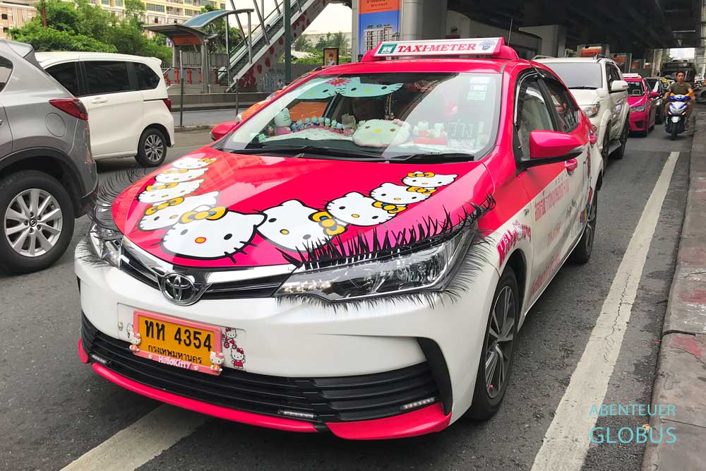 Taxi in verspielter Hello-Kitty-Gestaltung mit Aufklebern und Wimpern an den Scheinwerfern im Straßenverkehr in Bangkok, Thailand