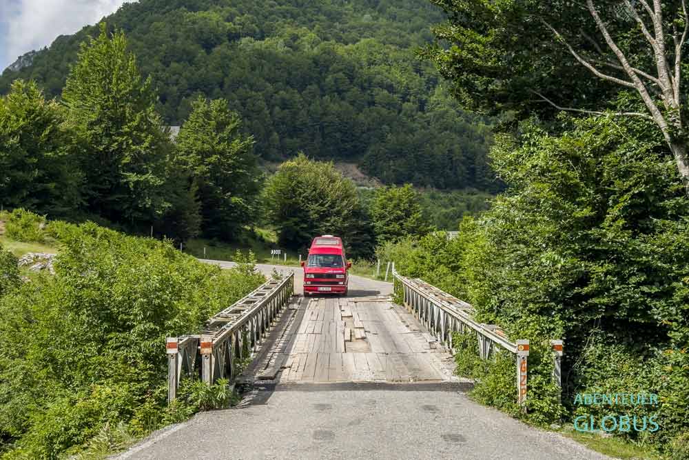 Rotes Wohnmobil auf einer Brücke über dem Bashkimit Canyon bei Vermosh