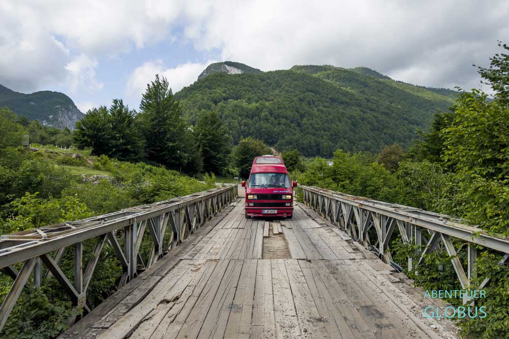 Roter Bulli VW T3 auf einer Brücke über dem Bashkimit Canyon bei Vermosh
