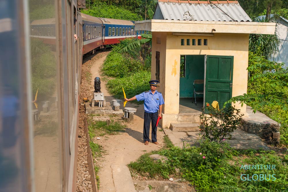 Weichensteller zeigt die gelbe Fahne als Zeichen für freie Fahrt des Wiedervereinigungsexpress in Vietnam