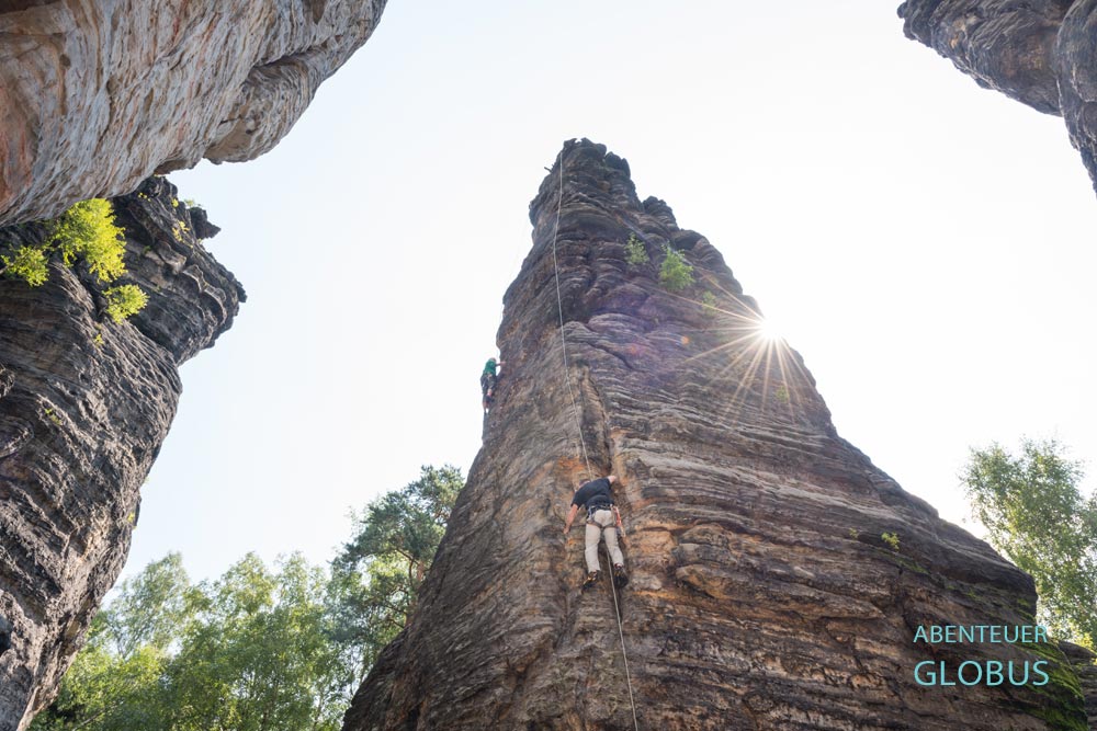 Kletterer an einer Felswand zwischen zwei anderen Felstürmen im Bielatal im Elbsandsteingebirge