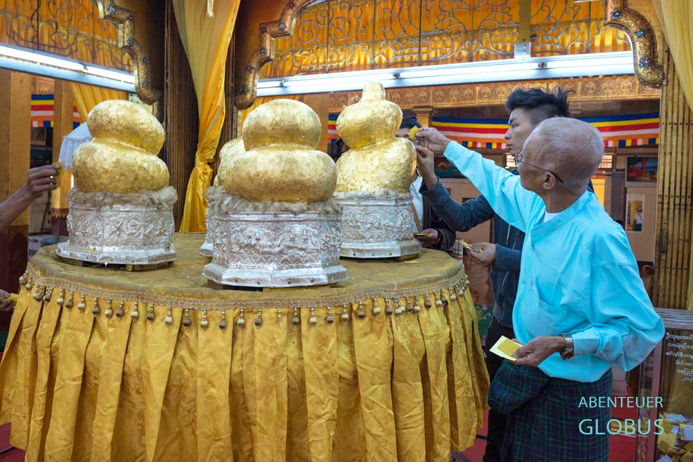 In der Gebetshalle der Phaung Daw U Pagode auf dem Inle-See spenden Gläubige Blattgold an die fünf goldenen Buddha-Statuen.