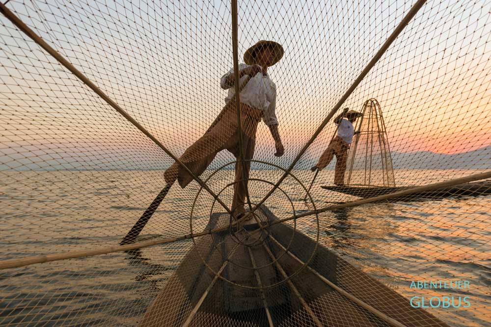 Intha-Fischer mit konischer Fischreuse im Sonnenuntergang auf dem Inle-See, fotografiert durch die Reuse.