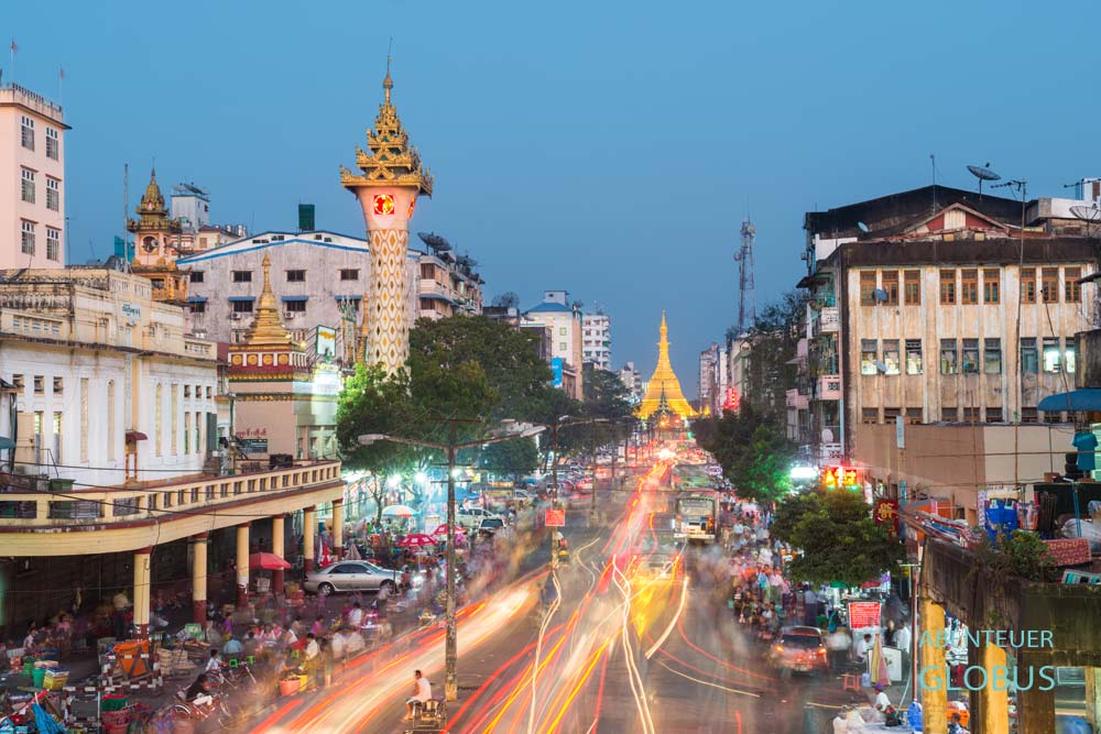 Verkehr auf der Maha Bandula Road mit Uhrturm und beleuchteter Sule-Pagode