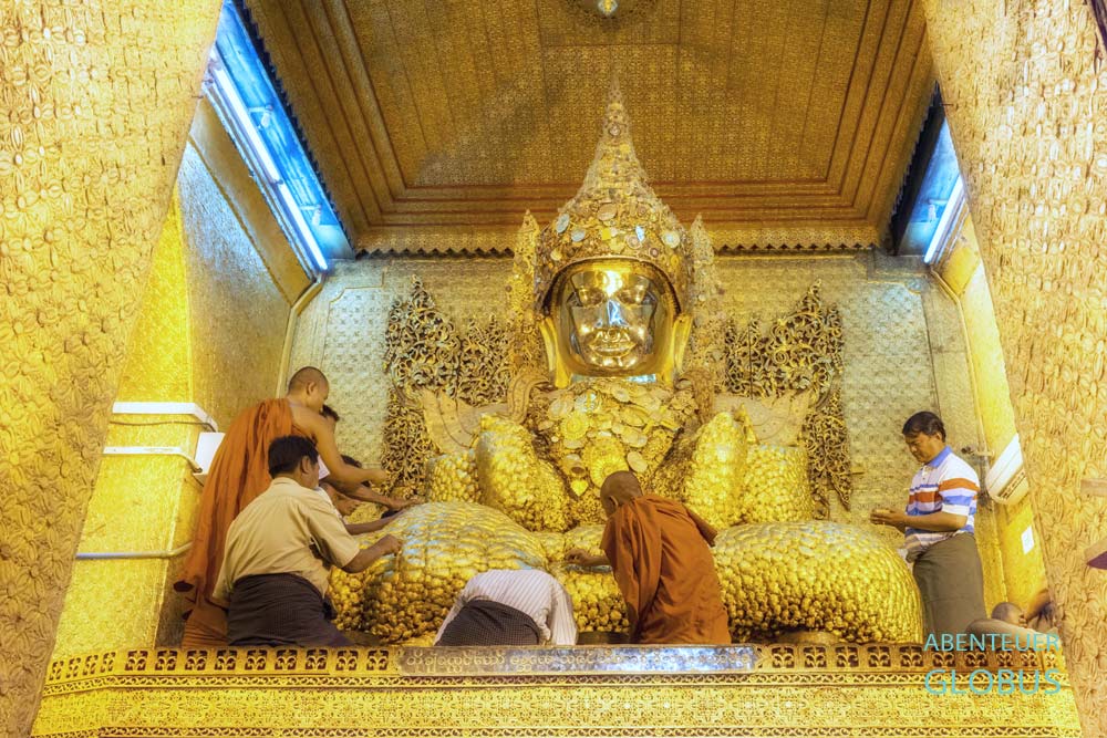 Gläubige Männer bringen Blattgold auf den Mahamuni-Buddha in der Mahamuni-Pagode in Mandalay