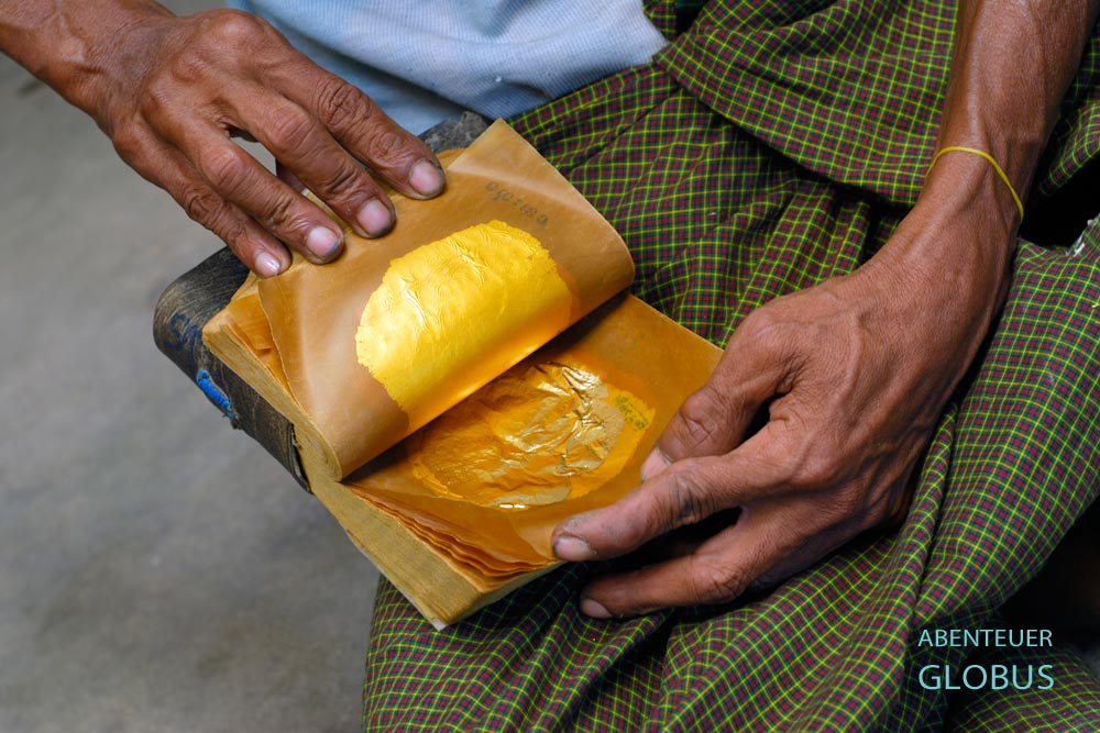 Männerhände halten ein geöffnetes Paket mit hauchdünnen Goldplättchen aus einer Blattgoldmanufaktur in Mandalay