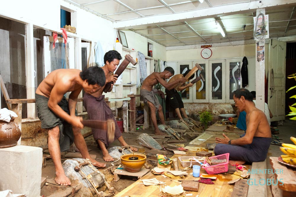 In einer Blattgoldmanufaktur in Mandalay bearbeiten Männer Gold mit Vorschlaghämmern, bis es hauchdünn wird.