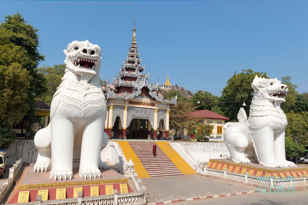 Mönch auf der Treppe zum Mandalay Hill zwischen zwei großen Löwenstatuen in Mandalay, Myanmar.