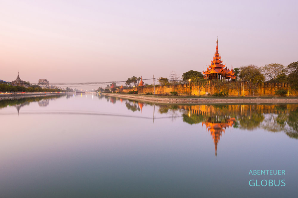 Ein breiter Wassergraben umgibt das Palastgelände mit den imposanten Mauern in Mandalay, Myanmar.