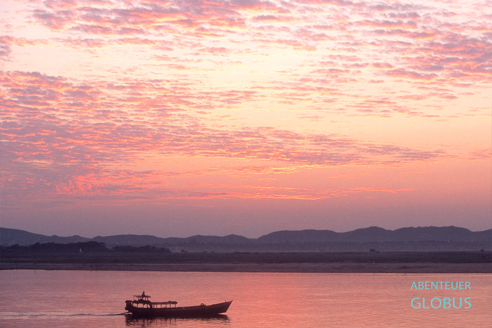 Boot auf dem Ayeyarwady-Fluss bei rotem Abendhimmel nach Sonnenuntergang in Mandalay, Myanmar
