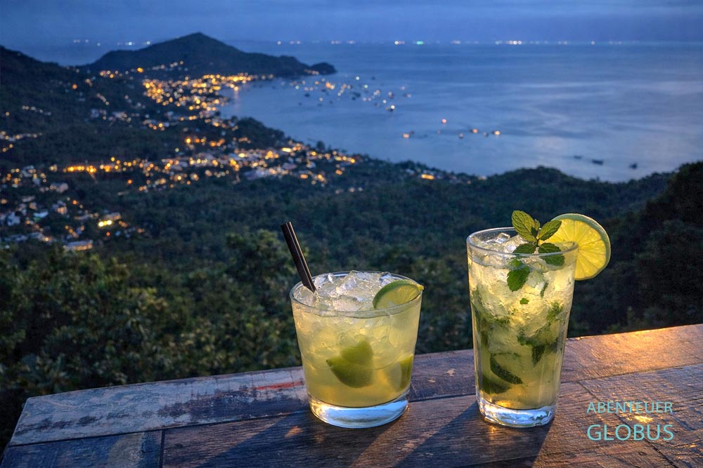 Mango Viewpoint: Zwei Cocktails mit Blick auf den beleuchteten Sairee Beach, Koh Tao, Thailand