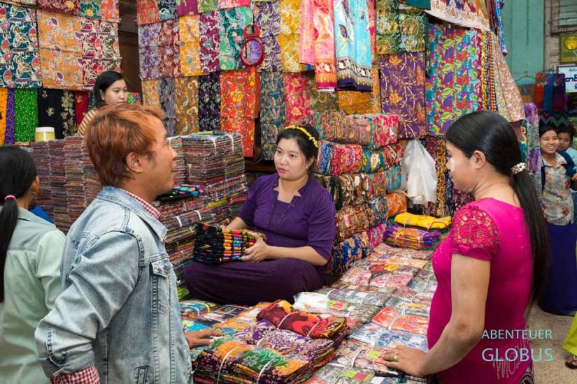 Im Zeigyo-Markt in Mandalay verkauft eine Frau bunte Stoffe aus ihrem Verkaufsstand.