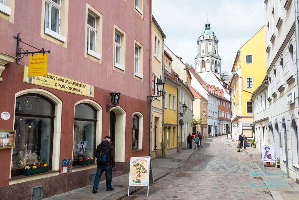 Leute und Häuser mit Geschäften in der Fleischergasse, im Hintergrund Turm der Frauenkirche in Meißen