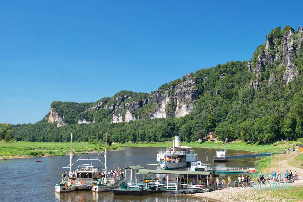 Touristen am Anleger der Gierseilfähre, im Hintergrund Schaufelraddampfer und Basteimassiv im Elbsandsteingebirge