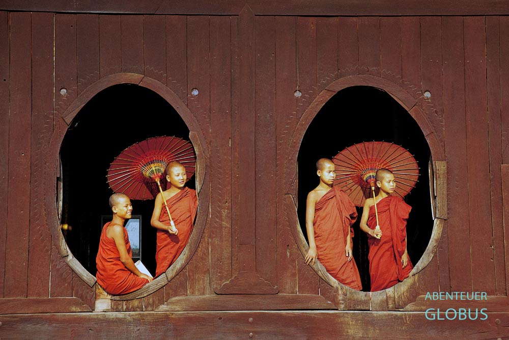Vier Mönche mit roten Bambusschirmen in ovalen Fenstern des Shwe Yan Bye Kloster am Inle-See