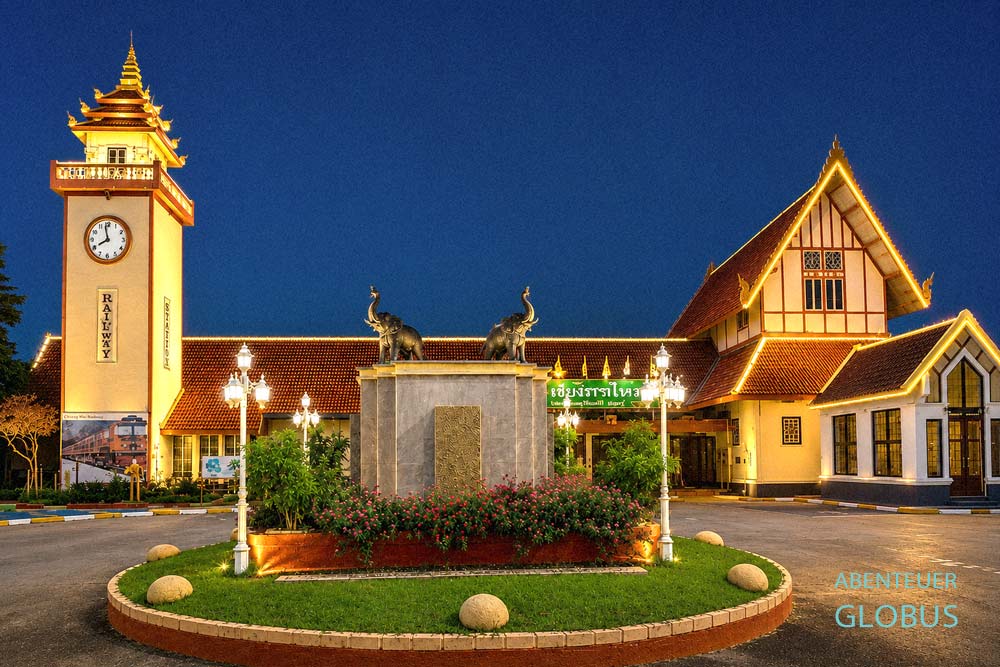 Die beleuchtete Fassade des Bahnhofs in Chiang Mai in der Nacht ohne Passagiere auf dem Vorplatz.